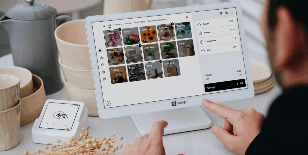Digitale Tablet-Kasse auf einem Tresen in einem Geschäft, im Hintergrund ist Ware (Geschirr) zu sehen, ein Mitarbeiter bedient die Kasse